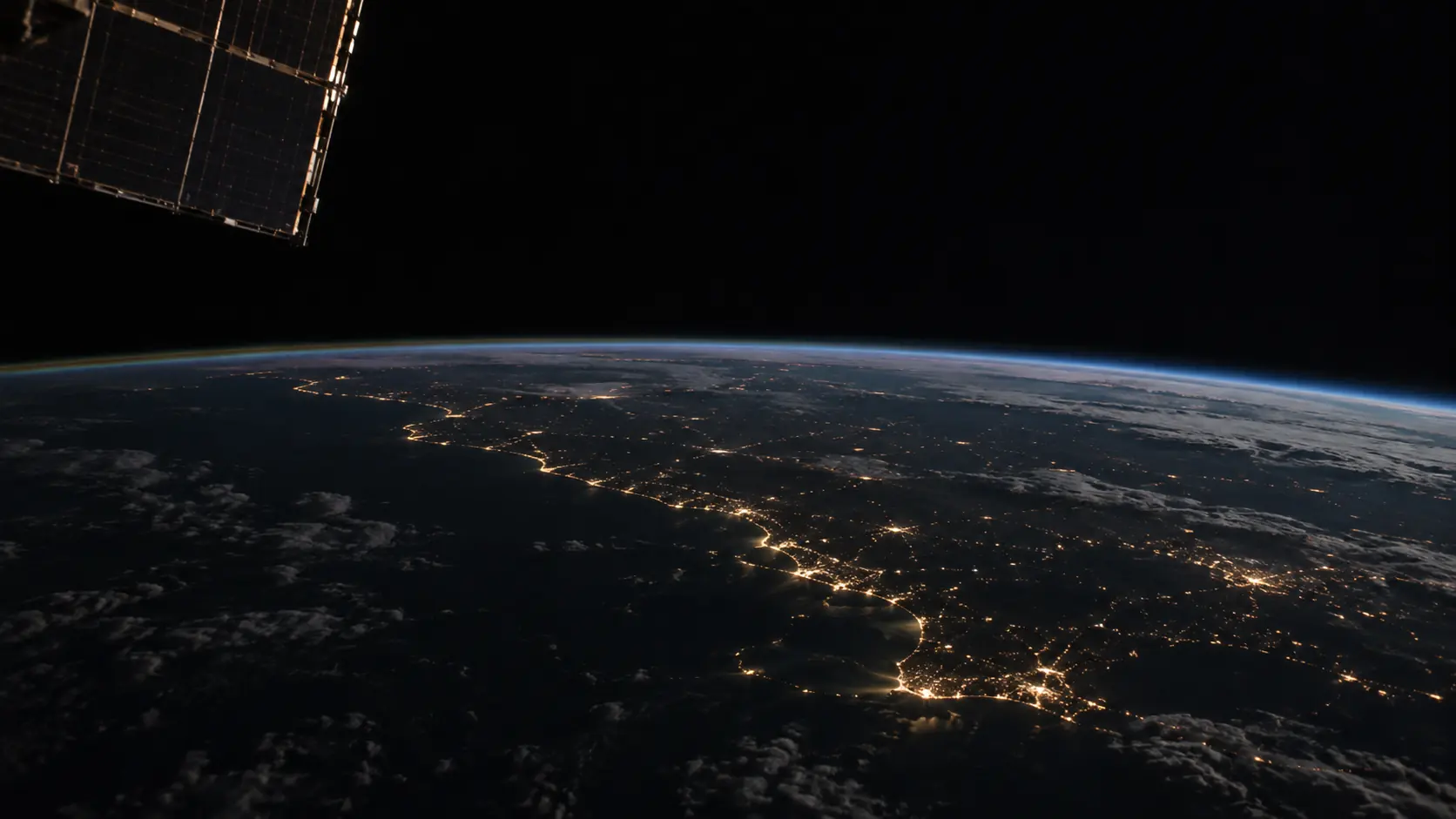La Tierra de noche vista desde la órbita, con luces de ciudades en la costa